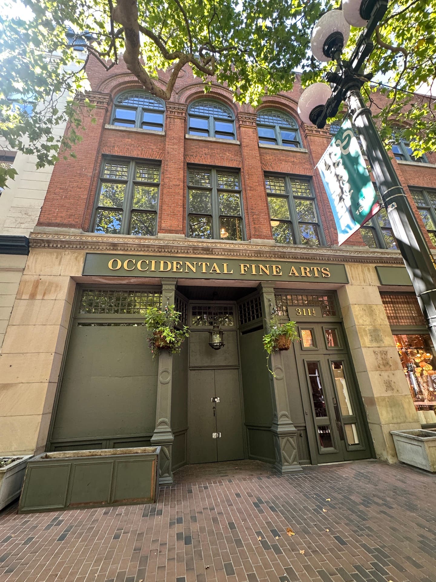 The Occidental Fine Arts Center on Occidental Avenue, Pioneer Square. A 19th-century brick building with tall arched windows and a green awning